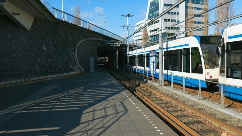 a blue and white train traveling under a bridge